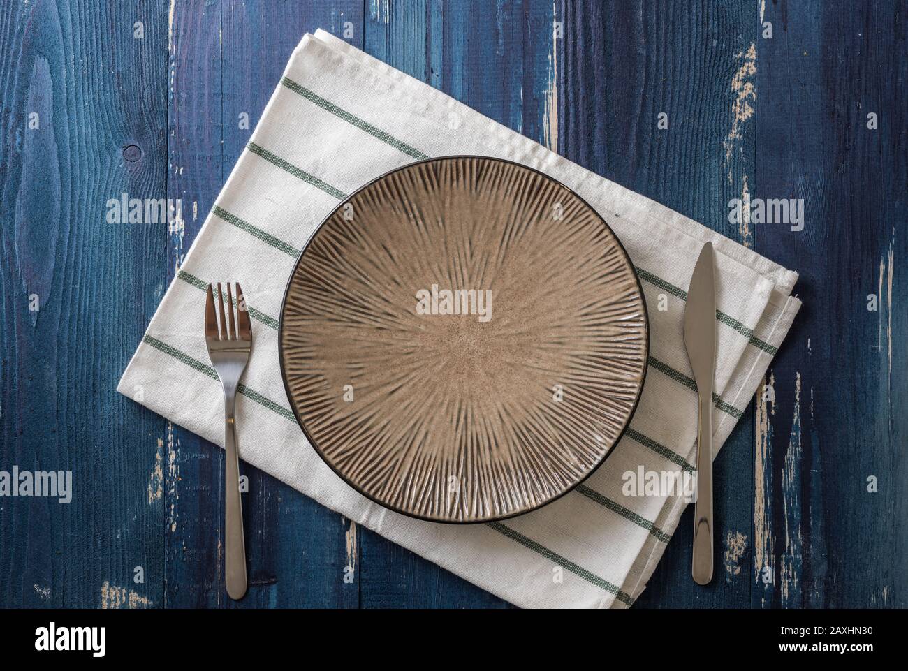 Round Plate with utensils and dish towel on ocean blue wooden table background Stock Photo