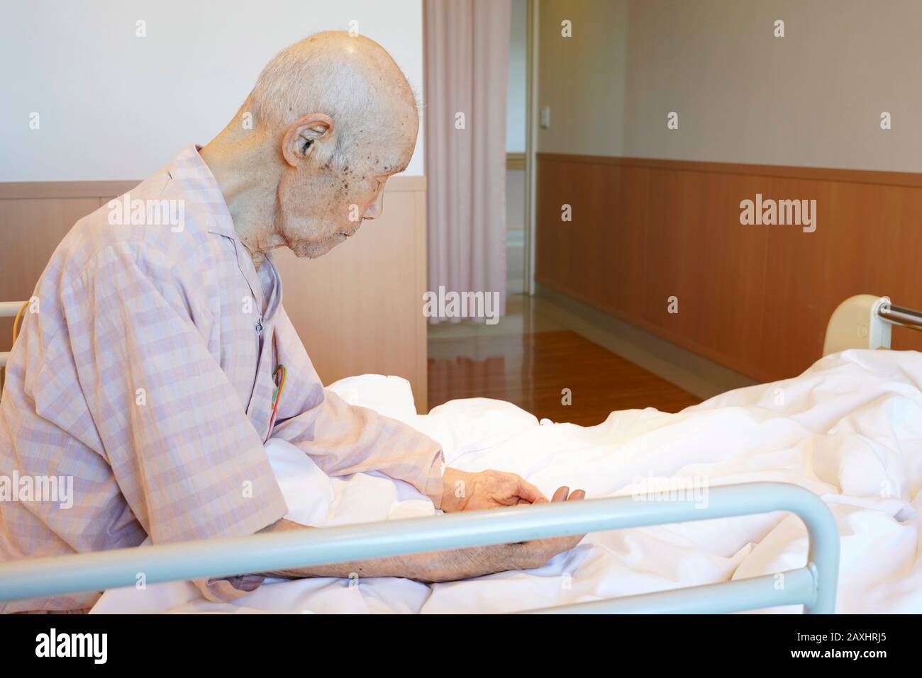 Jaoanese elderly man patient sitting on bed in hospital Stock Photo