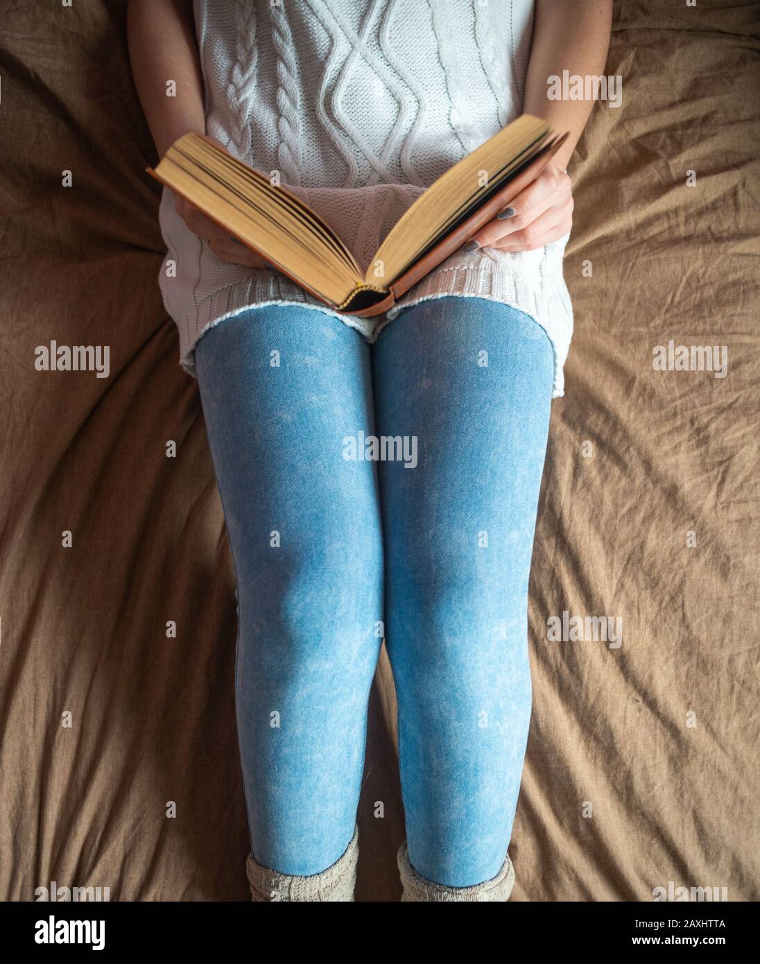 Young girl laying on bed reading , top view concept of cozy weekends & holidays. Stock Photo