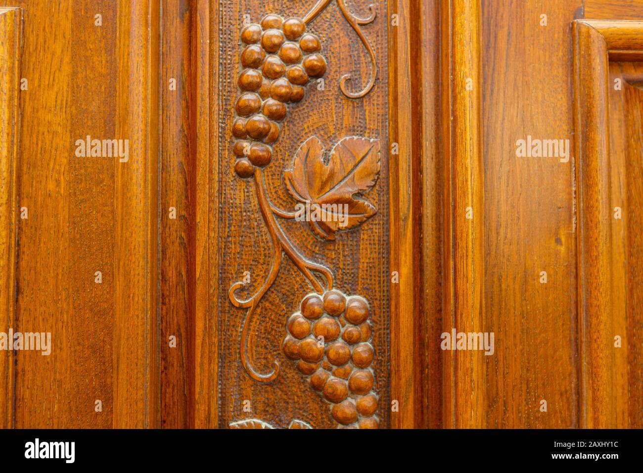 Bunches and leaves of grapes are carved on the wooden front door ...