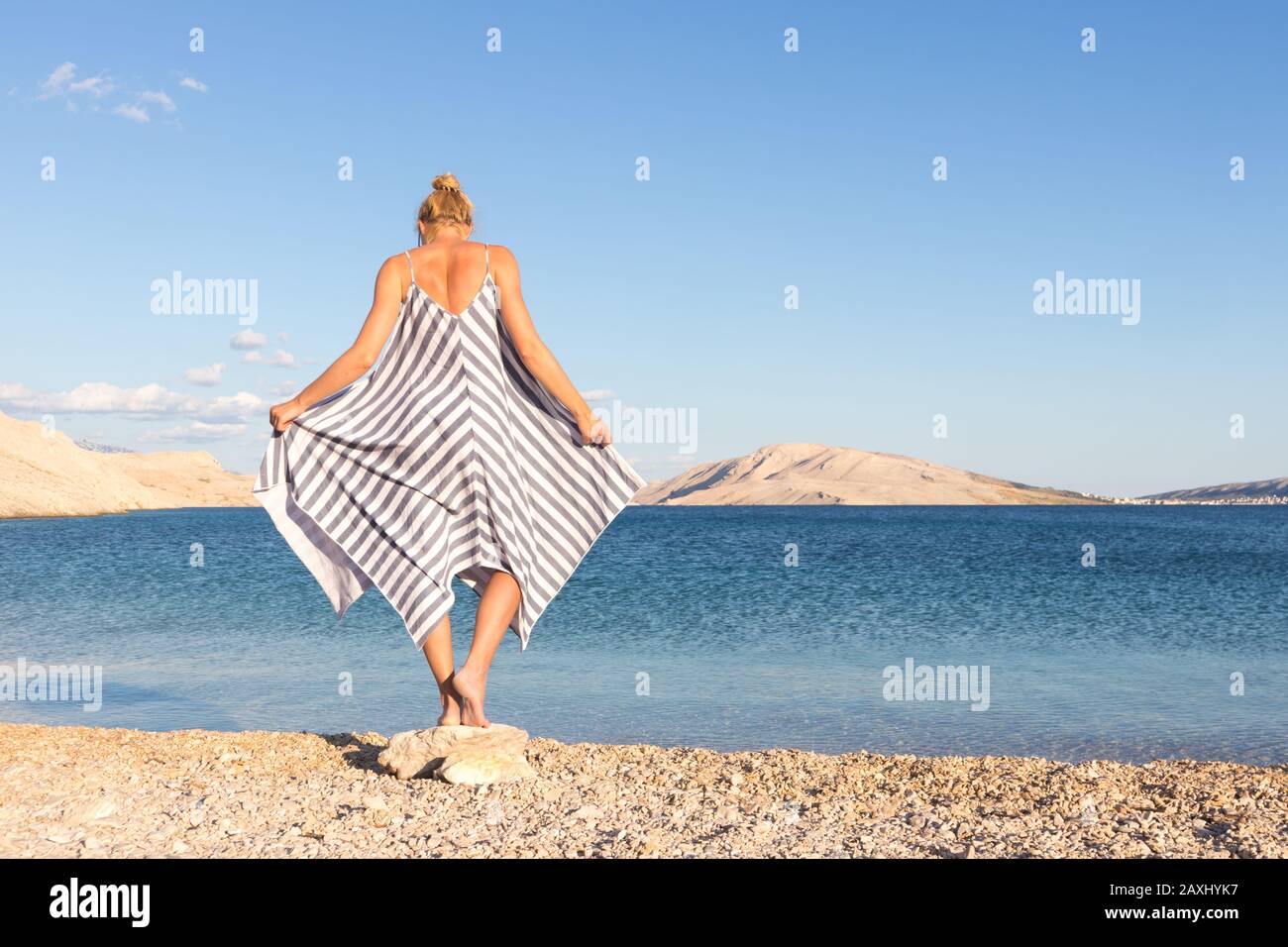 Happy carefree woman enjoying late afternoon walk on white pabbled beach on Pag island, Croatia Stock Photo