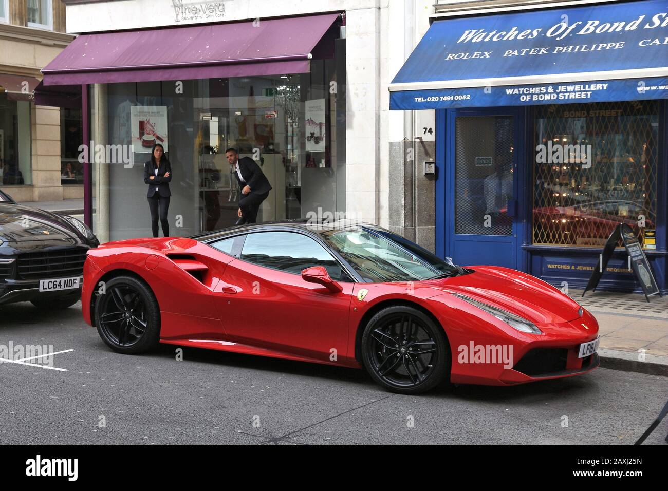 LONDON, UK - JULY 7, 2016: People look at Ferrari sports car parked at Bond Street in London. Bond Street is a major shopping street in the West End o Stock Photo