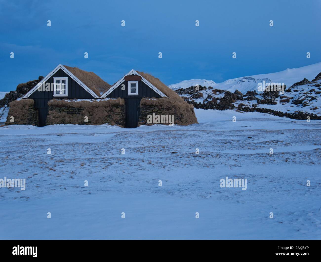 Two small wooden houses protected by a thick wall of peat Stock Photo