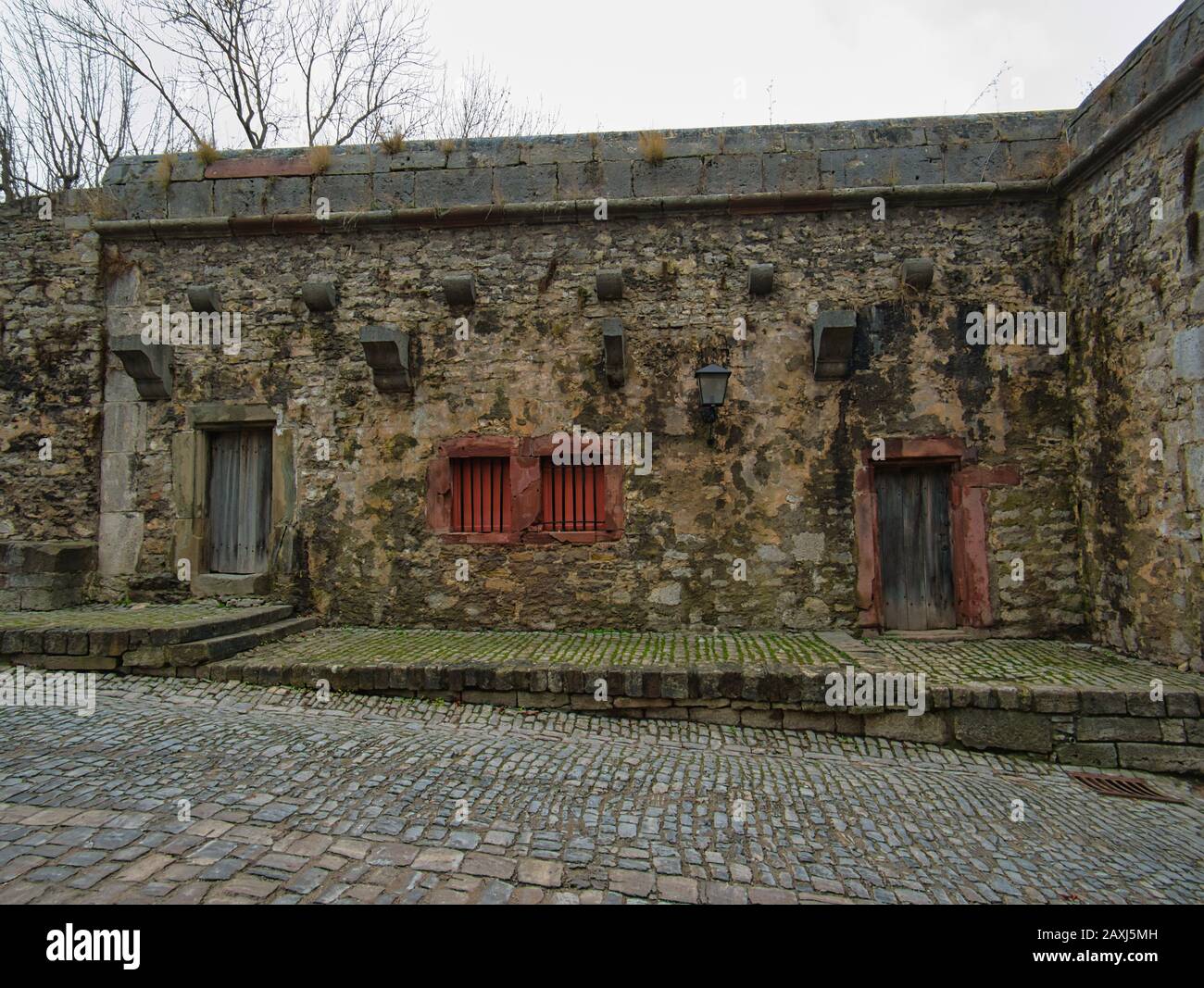 An old stone house with windows and doors integrated into a fortress wall Stock Photo