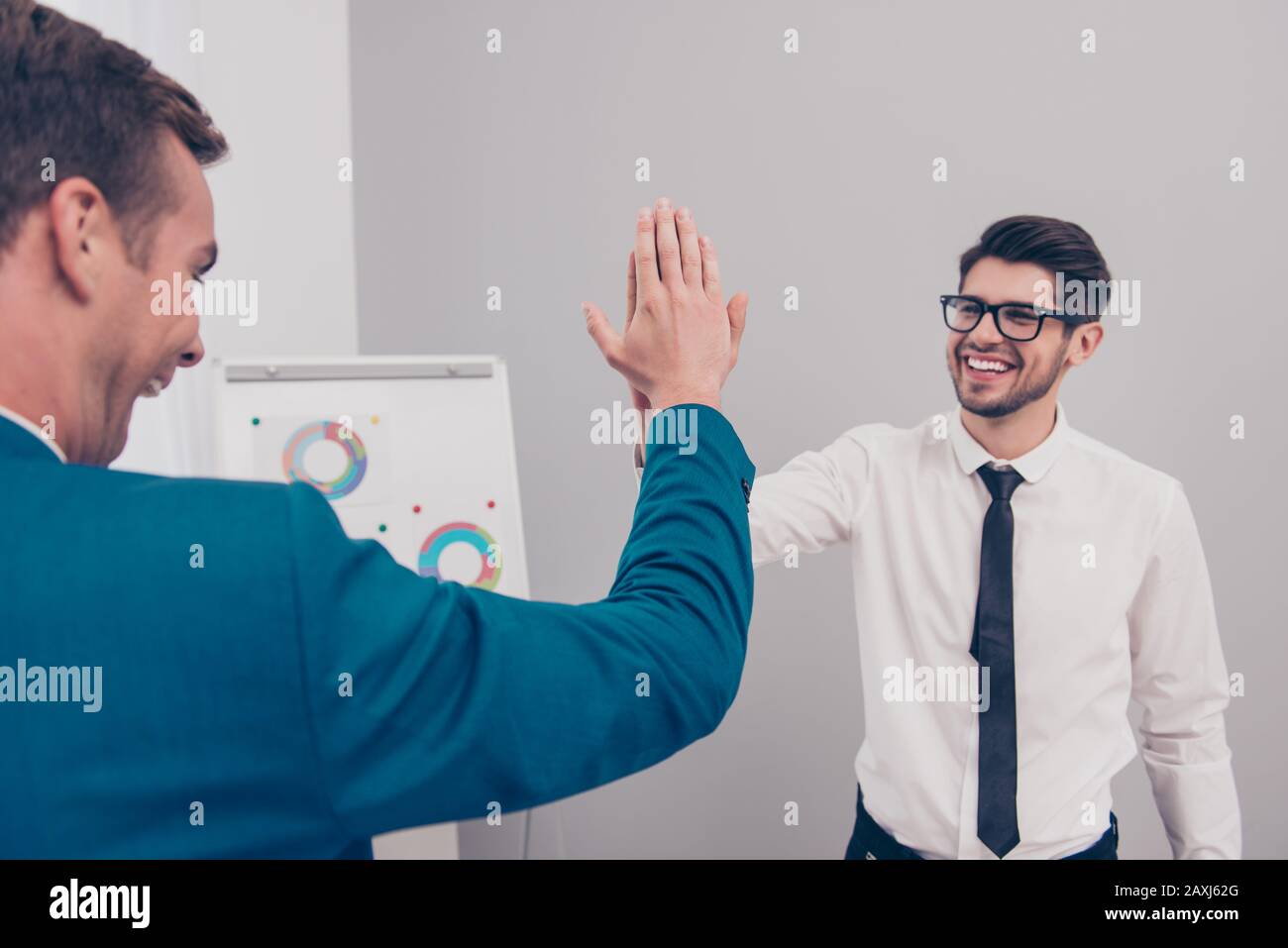 Portrait of happy young businessman giving high five to his colleague ...