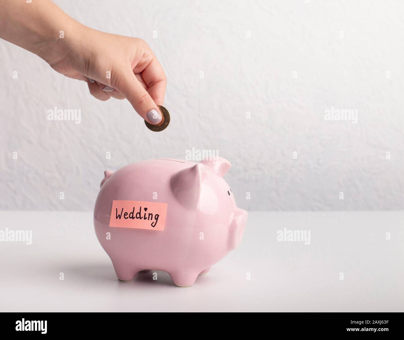 Hand putting a coin into piggy bank with wedding text Stock Photo - Alamy