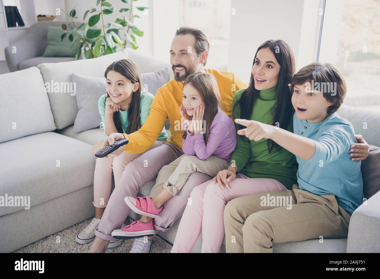 Dream harmony family spending time concept. Five people dad daddy mom mommy three kids boy girls sit divan watch tv schoolboy point index finger hold Stock Photo