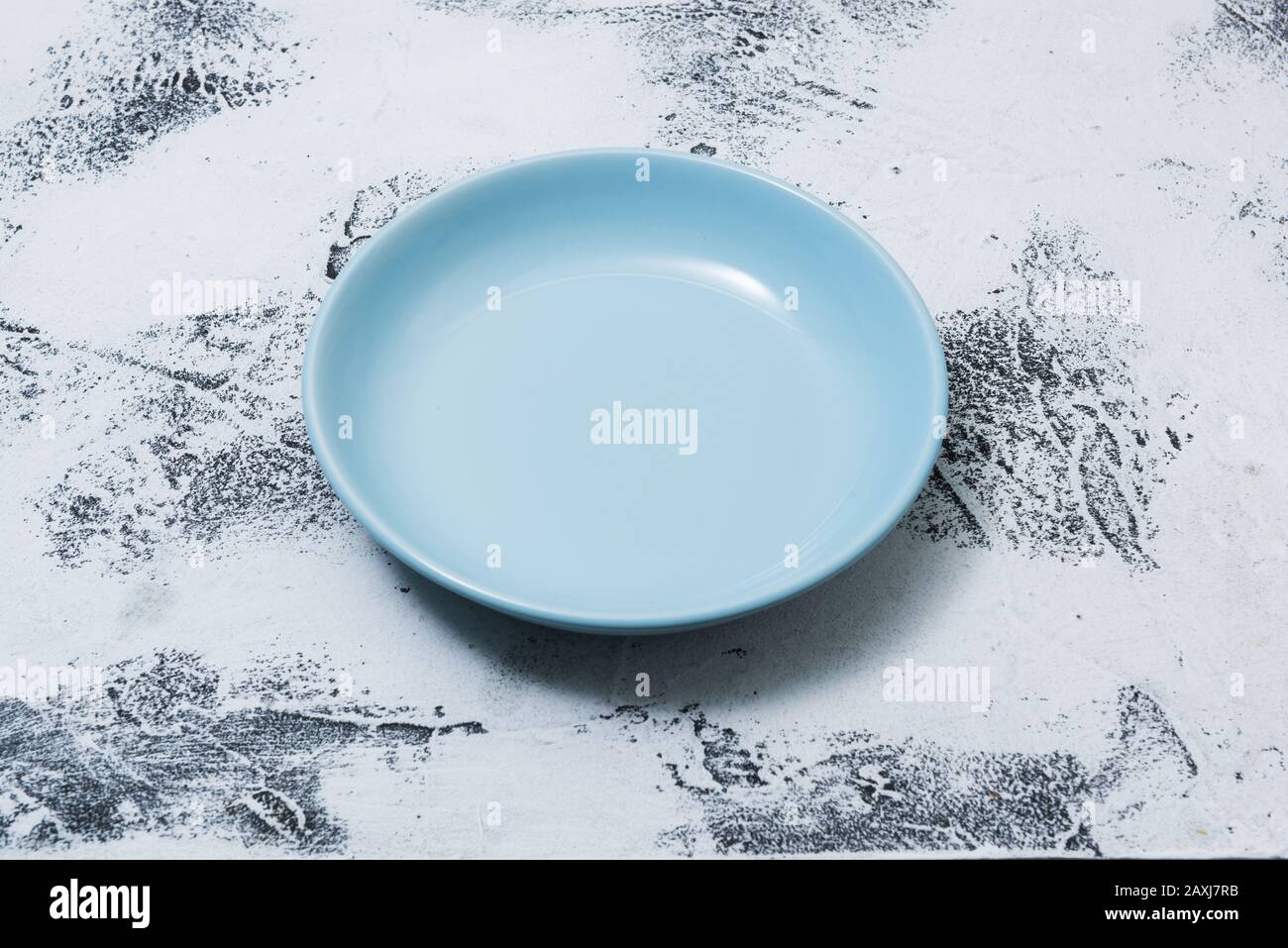 Blue Round Plate on white abstract scraped wooden table background side view Stock Photo