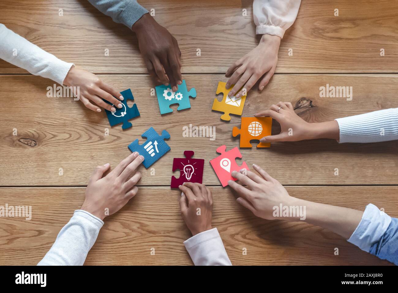 Hands of international coworkers putting colorful puzzles together Stock Photo