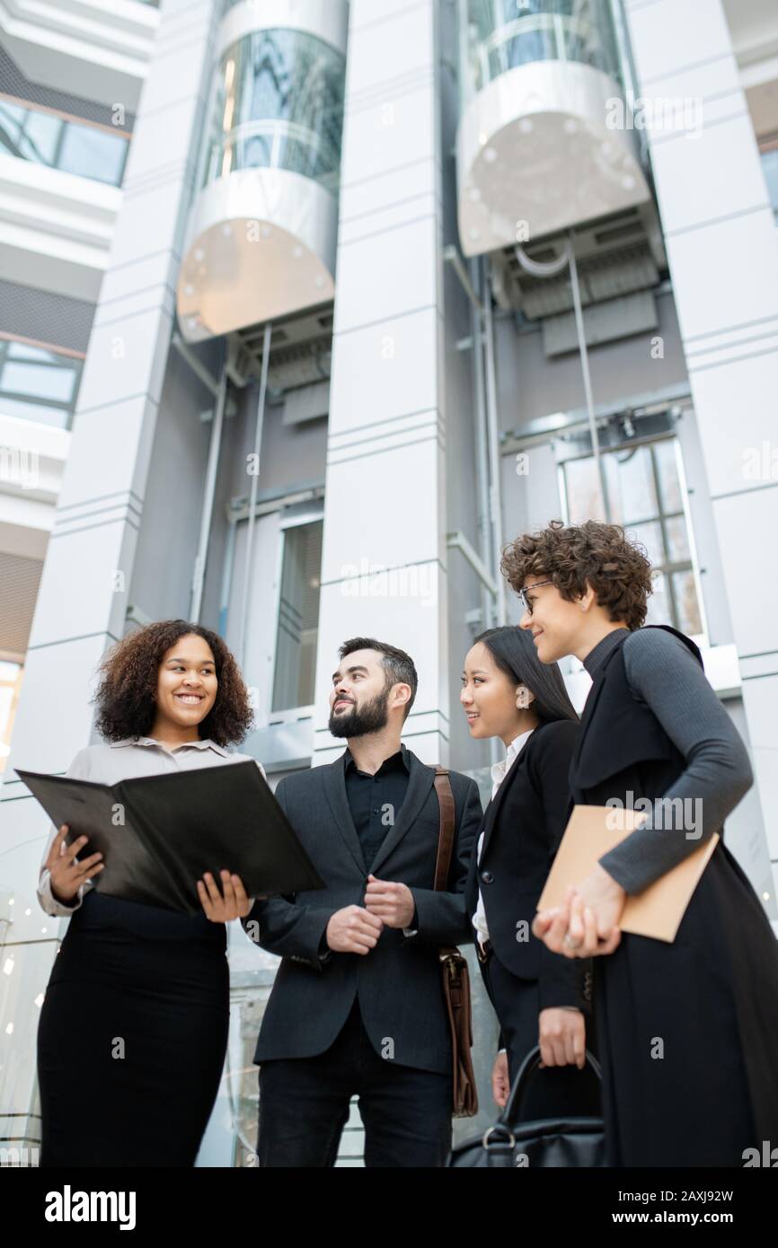 Smiling Afro-American manager holding open folder while presenting project plan to colleagues in office Stock Photo