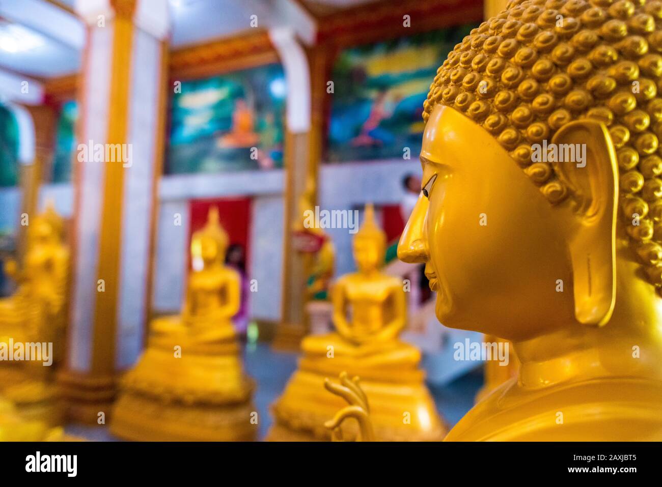 Wat Chalong,Phuket/Thailand-15December2019: Detail shot inside the first floor of the grand pagoda with statues in gold of lord buddha praying Stock Photo