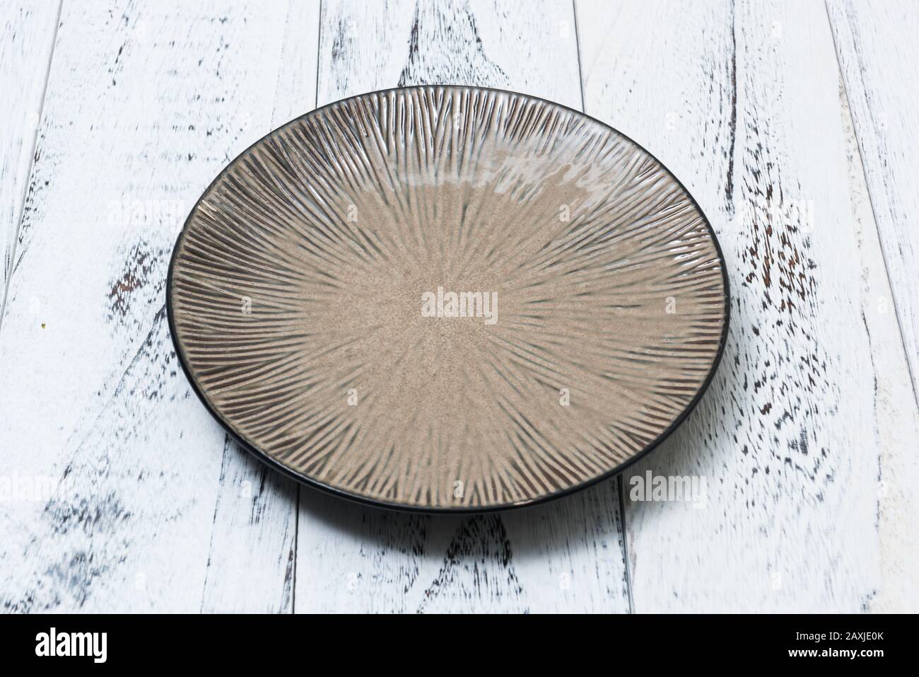 Round Plate on white abstract scraped wooden table background side view Stock Photo
