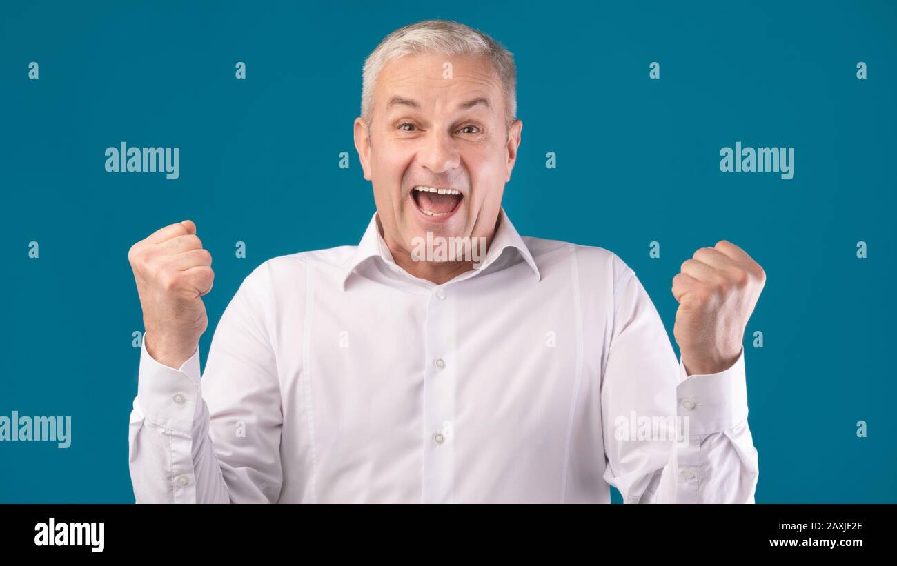 Mature man shouting over blue studio background Stock Photo