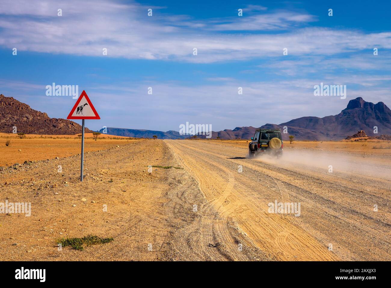 Car passing a Giraffes warning road sign in the desert of Namibia Stock Photo