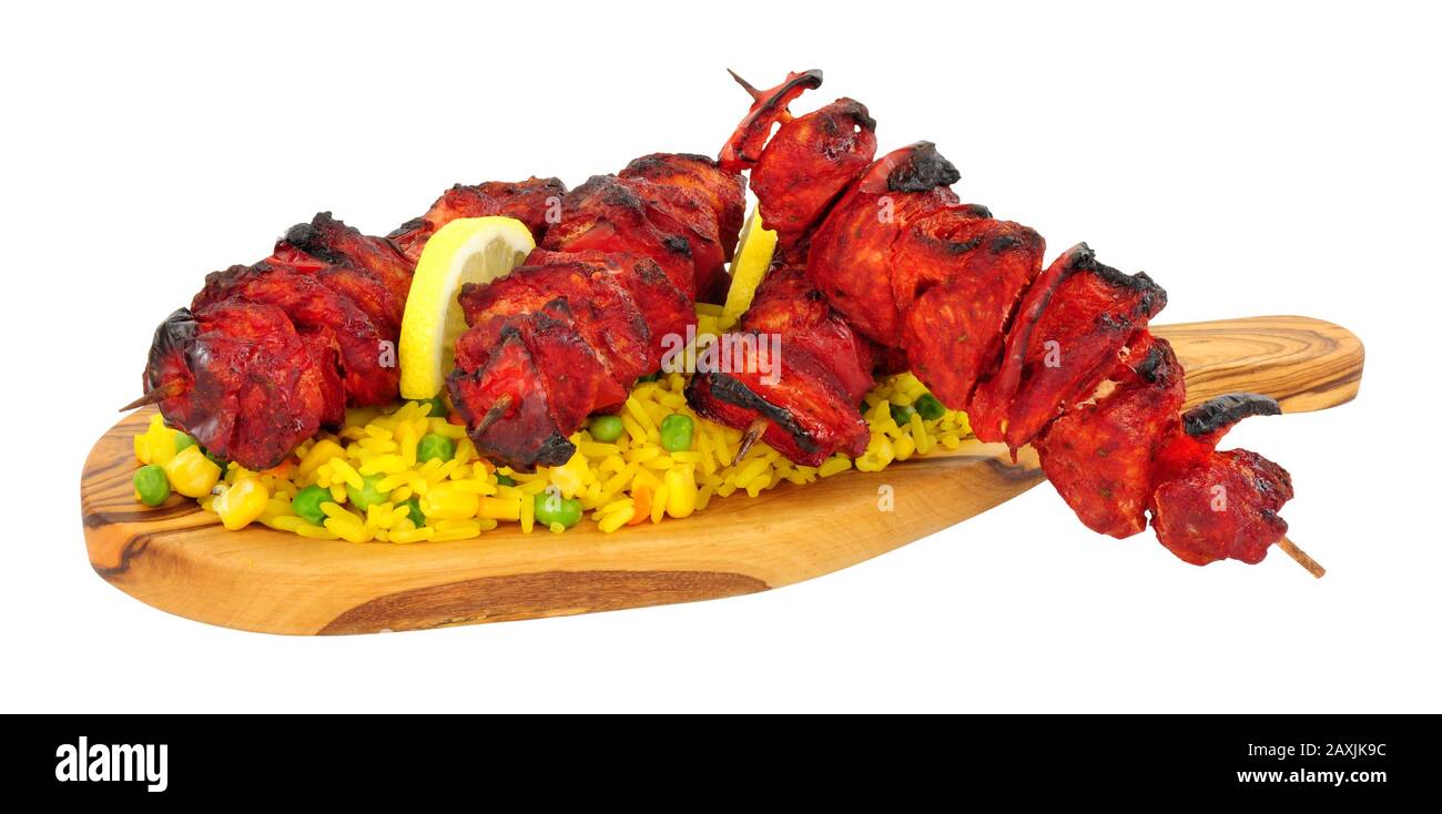 Tandoori turkey meat kebabs and vegetable rice on an olive wood serving board isolated on a