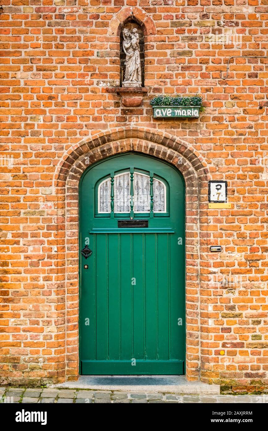 25 September 2018: Bruges, Belgium - Attractive door of an old house in Bruges with a statue of Virgin and Child in a niche above. Stock Photo