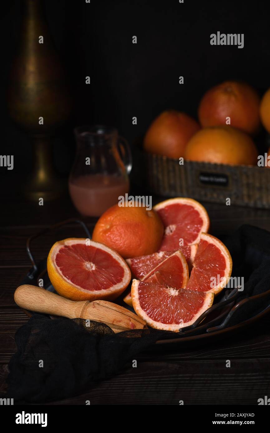 Slices of fresh grapefruit prepared for making fresh squeezed juice on a platter, dark background Stock Photo