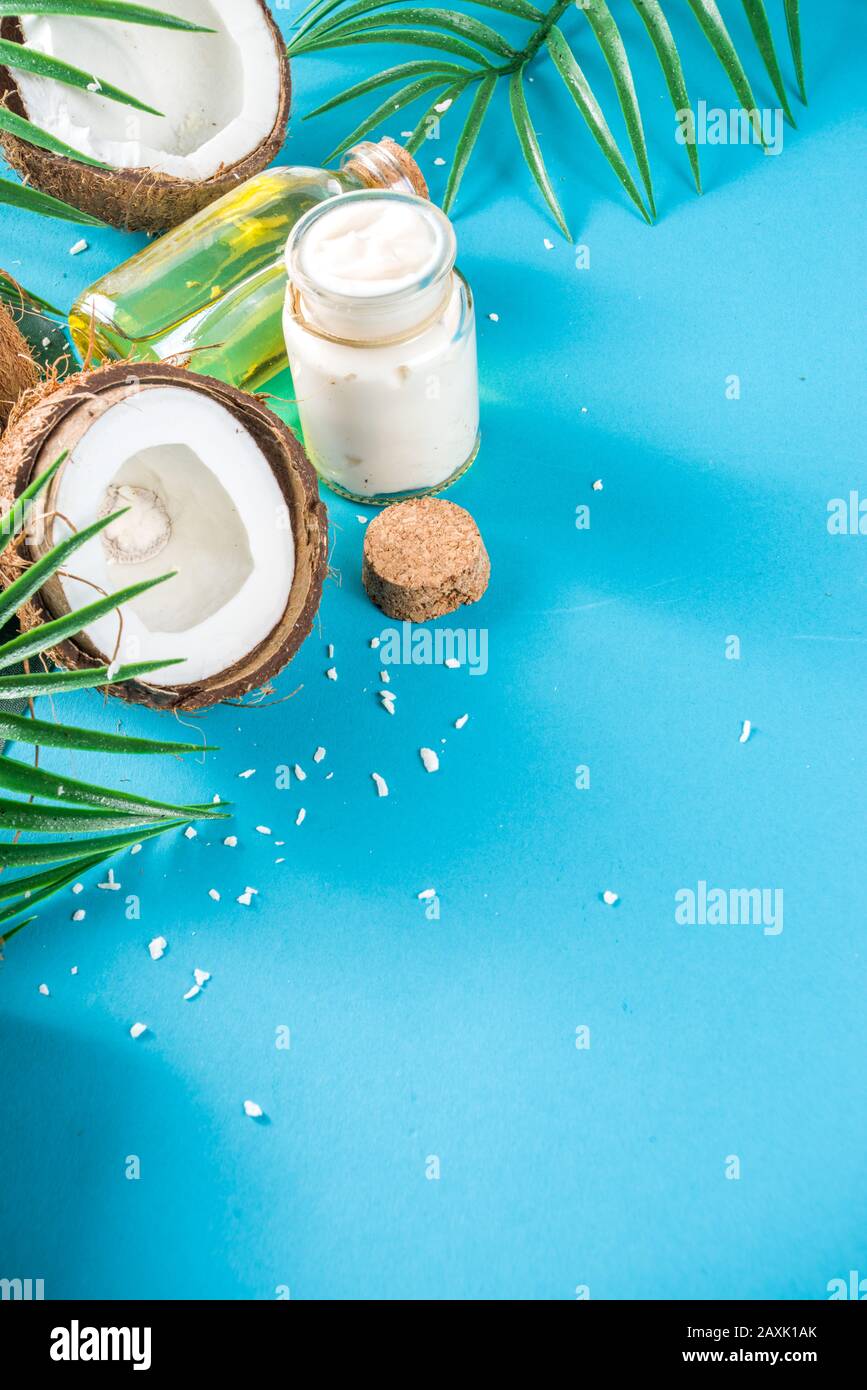 Coconut oil in glass jar with tropical leaves and fresh coconut