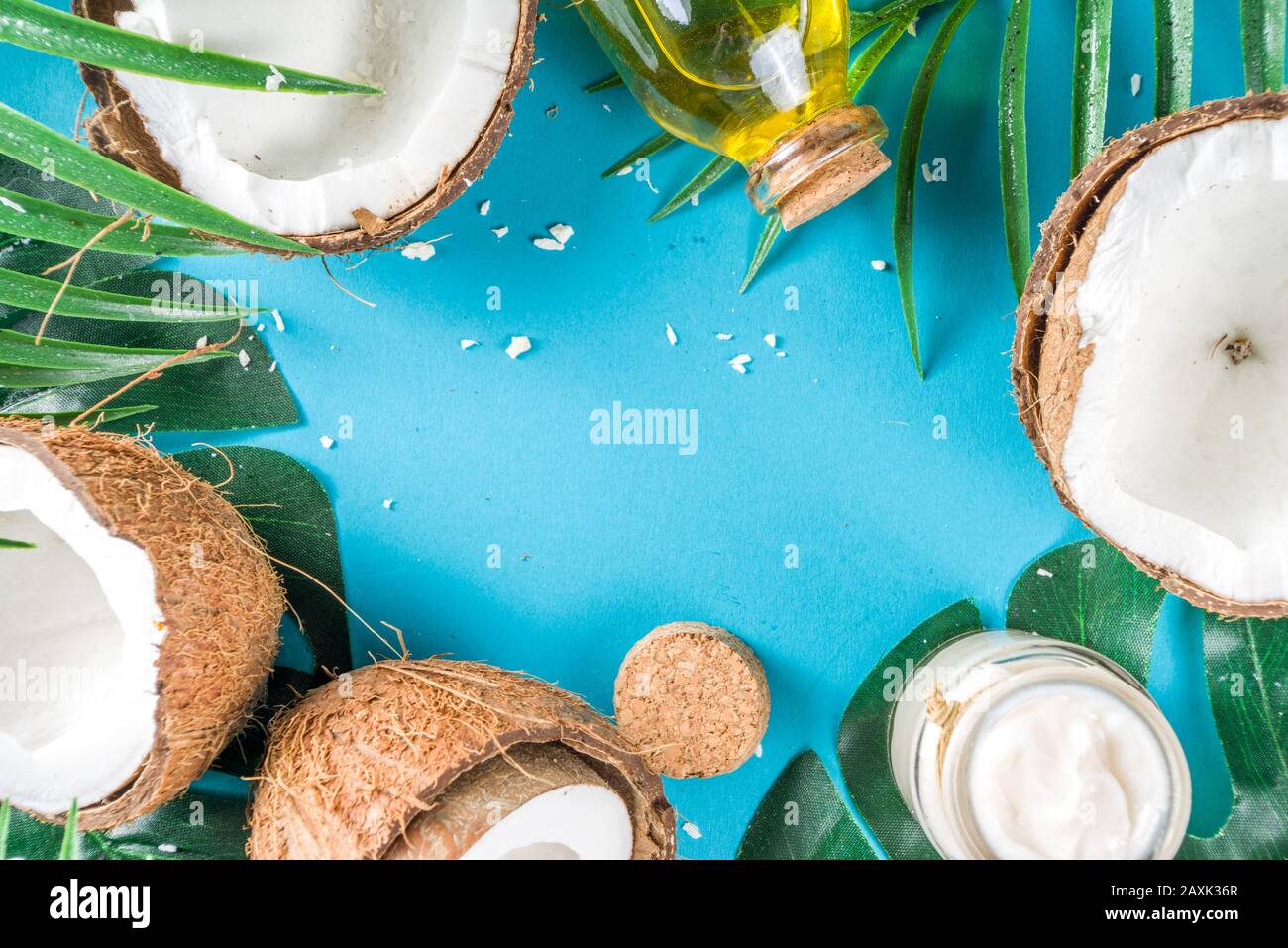 Coconut oil in glass jar with  tropical leaves and fresh coconut. Organic mct oils concept. turquoise, aquamarine background Stock Photo