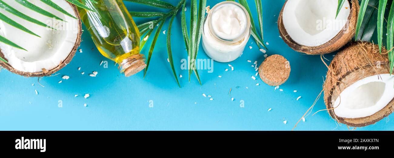 Coconut oil in glass jar with tropical leaves and fresh coconut