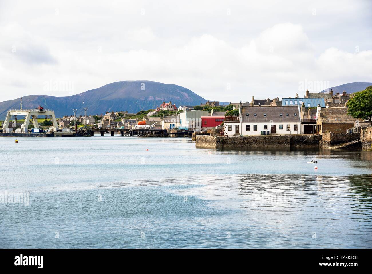 Waterfront of a coastal town on a cloudy spring day. A mountain is visible in background. Stock Photo