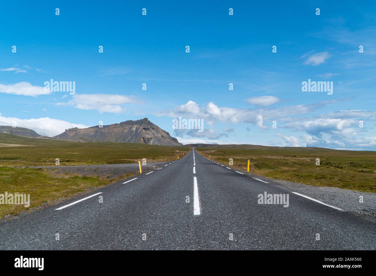Endless straight road in Iceland on a sunny day with a few clouds Stock Photo