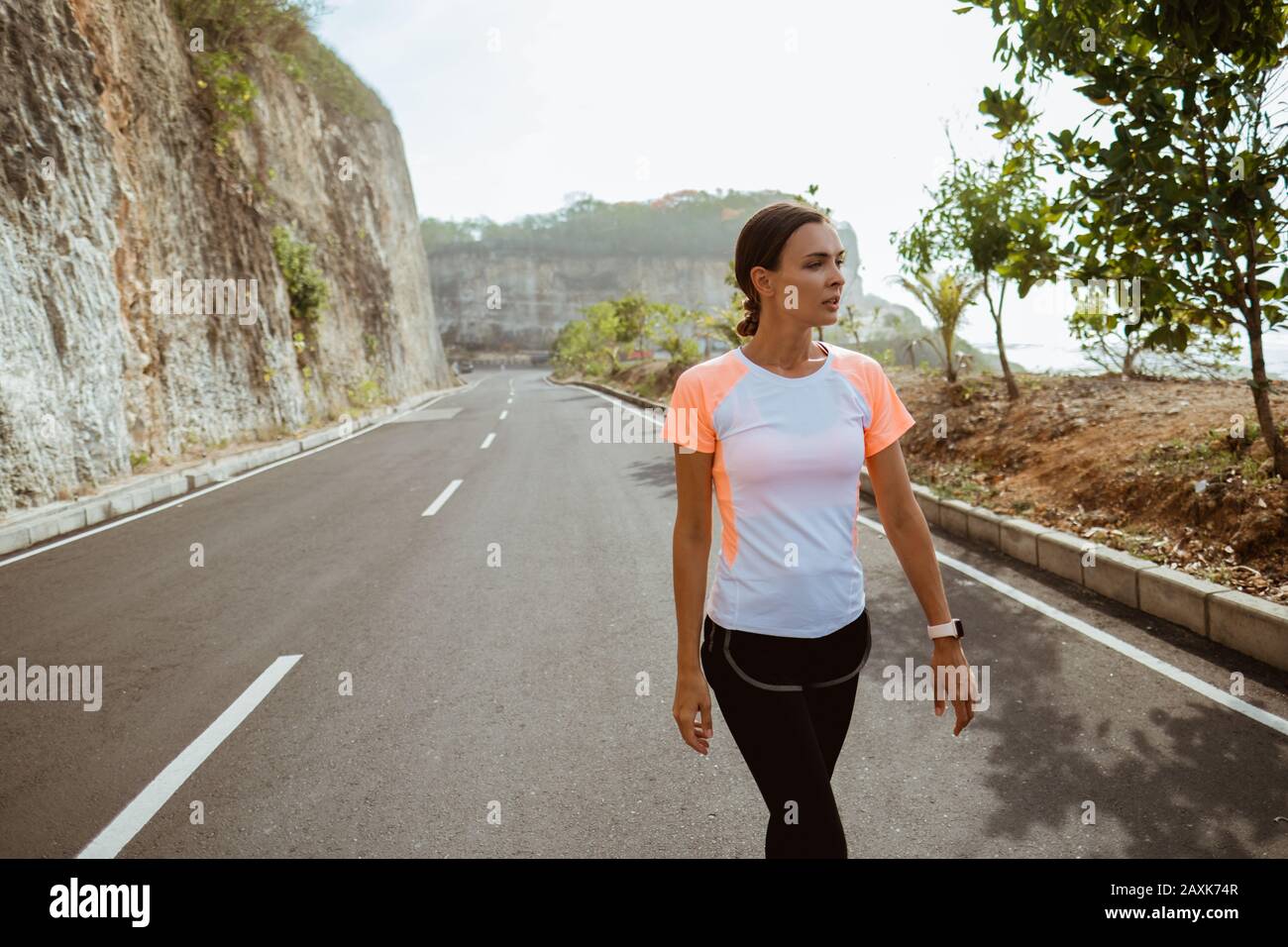 Fitness sport girl resting after intensive run walking on empty road ...