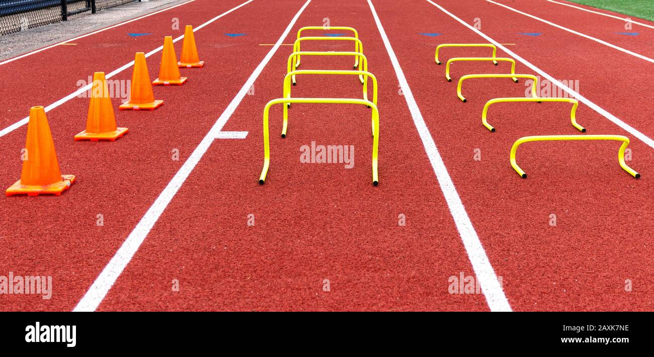 Cones and mini hurdles set up in lanes on a track for speed and agility