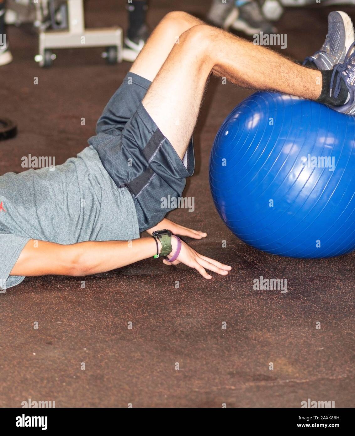 A runner is doing core exercising with his feet on top of a large blue