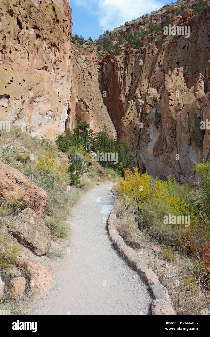 Pathway along the main loop trail at the base of cliffs in Frijoles Canyon at Bandelier National Monument near Los Alamos, New Mexico in autumn Stock Photo