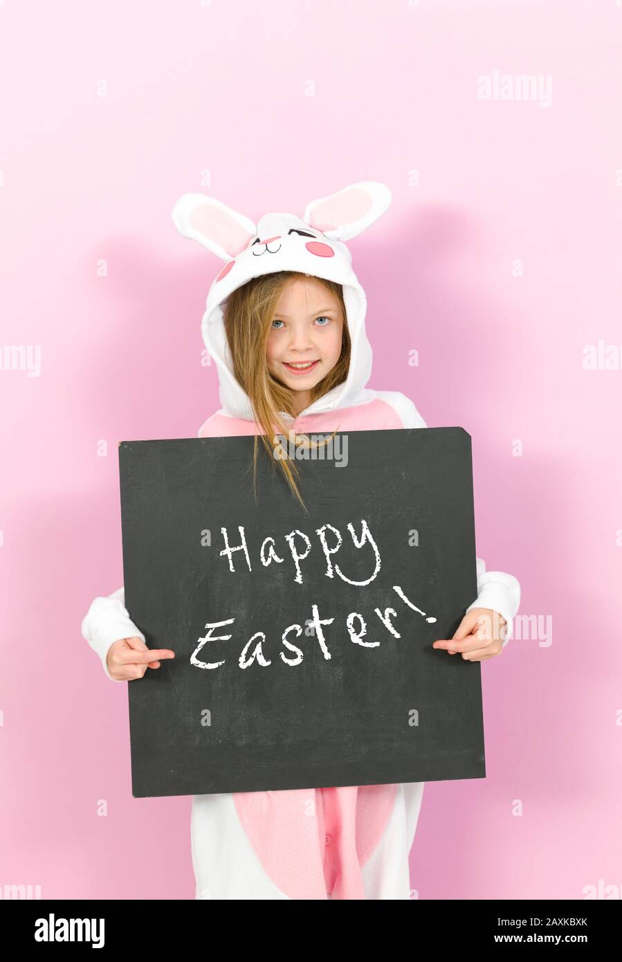 pretty blonde girl with cozy rabbit costume and blackboard with the words happy easter is posing in the studio and is happy Stock Photo