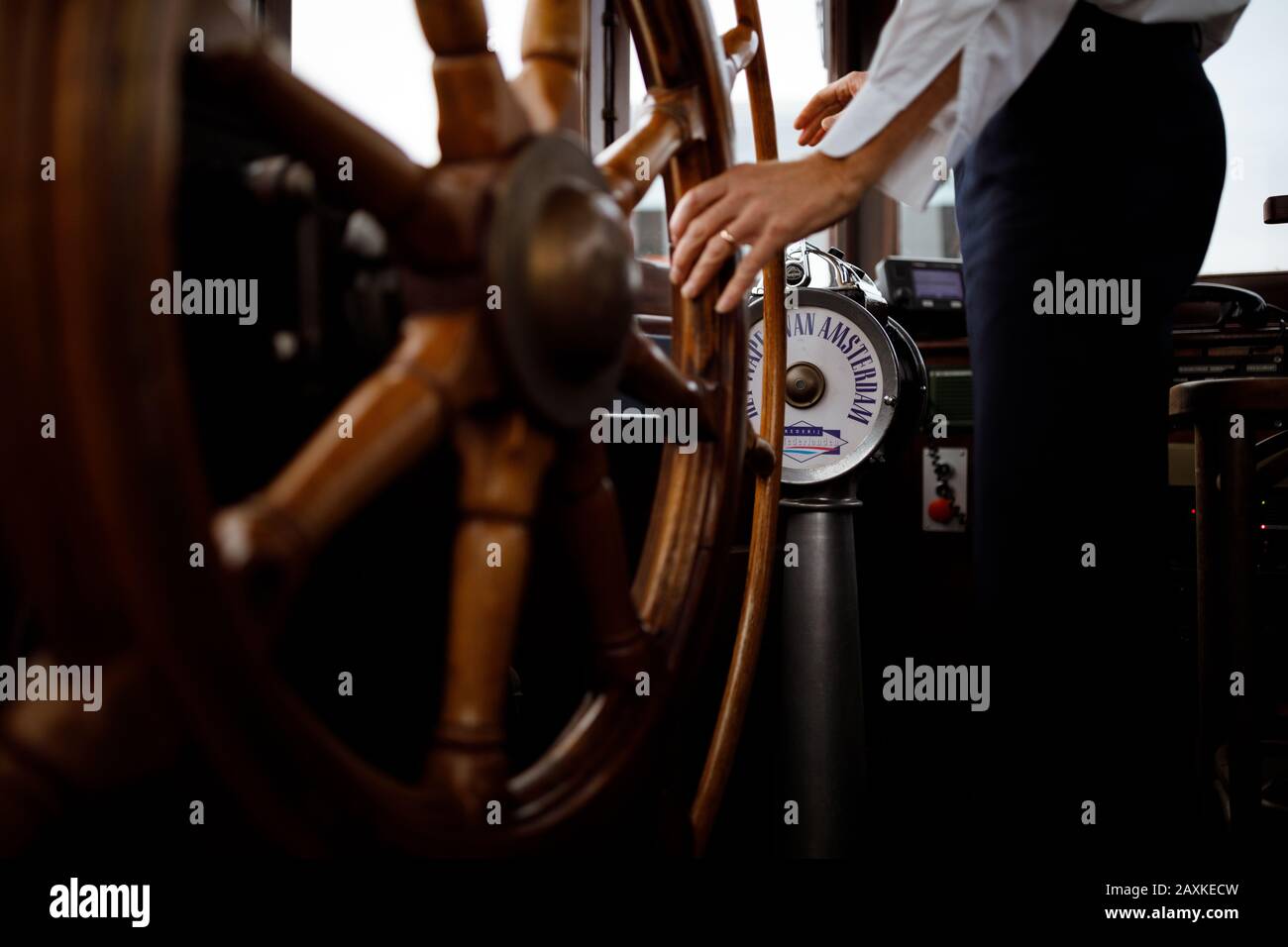 Captain steering a vintage boat standing behind a wooden wheel Stock