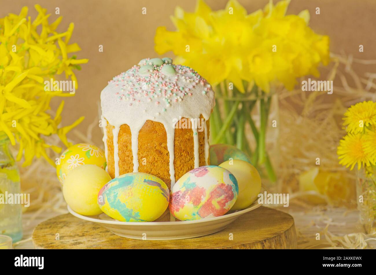 Cake with sprinkles and easter eggs. Easter cake by festive attributes. Easter composition with cake, coloured eggs and flowers Stock Photo