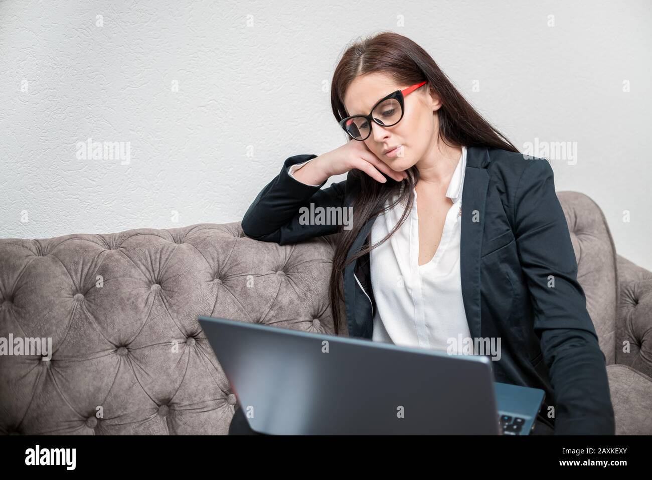 Businesswoman thinking about investments on laptop at home office Stock Photo