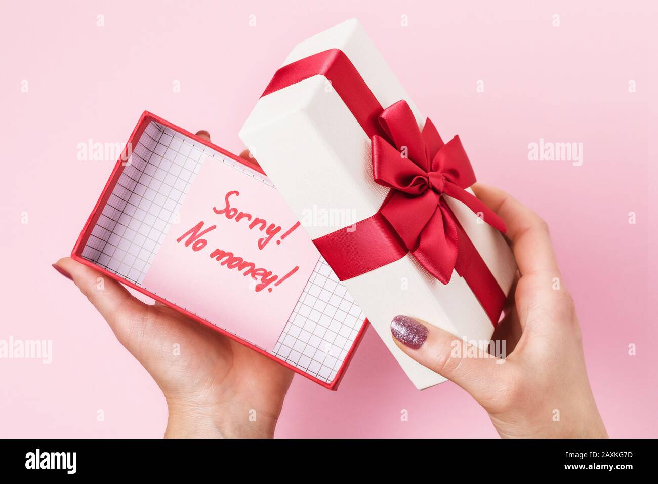 Girl opens a box with a gift on a pink background, top view. Concept on the topic of lack of money to buy gifts Stock Photo