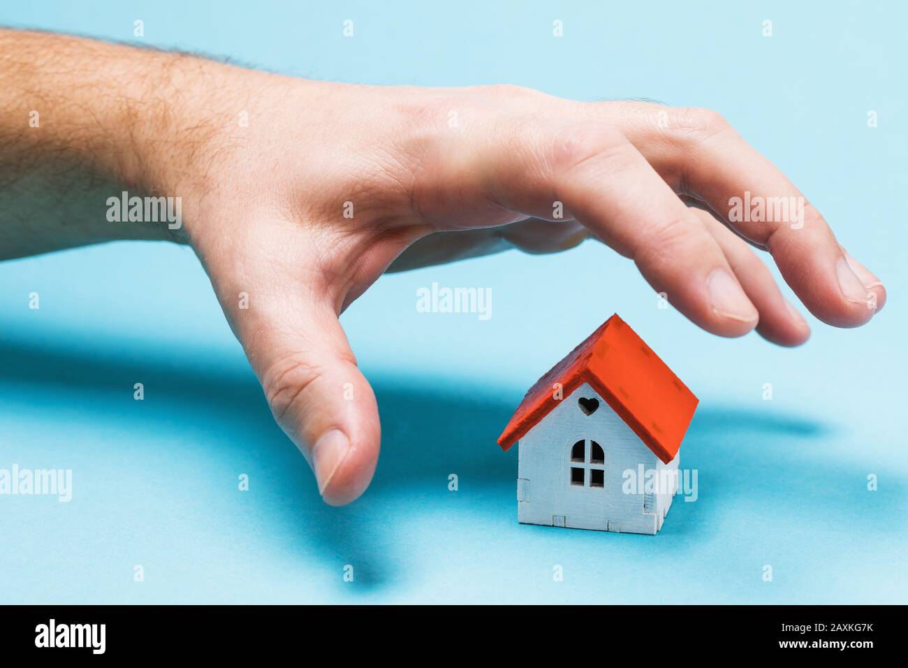 A hand reaches for a toy house. The concept of fraud and theft Stock Photo