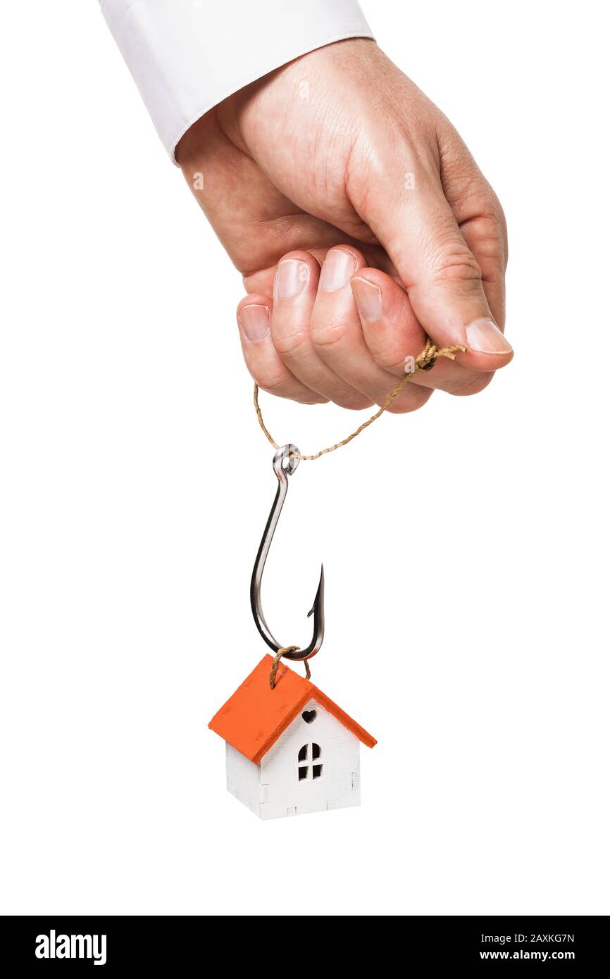 A man holds in his hand a fishing hook, for which a toy house is suspended. Concept on the topic of payment of mortgage lending. Isolated on a white b Stock Photo
