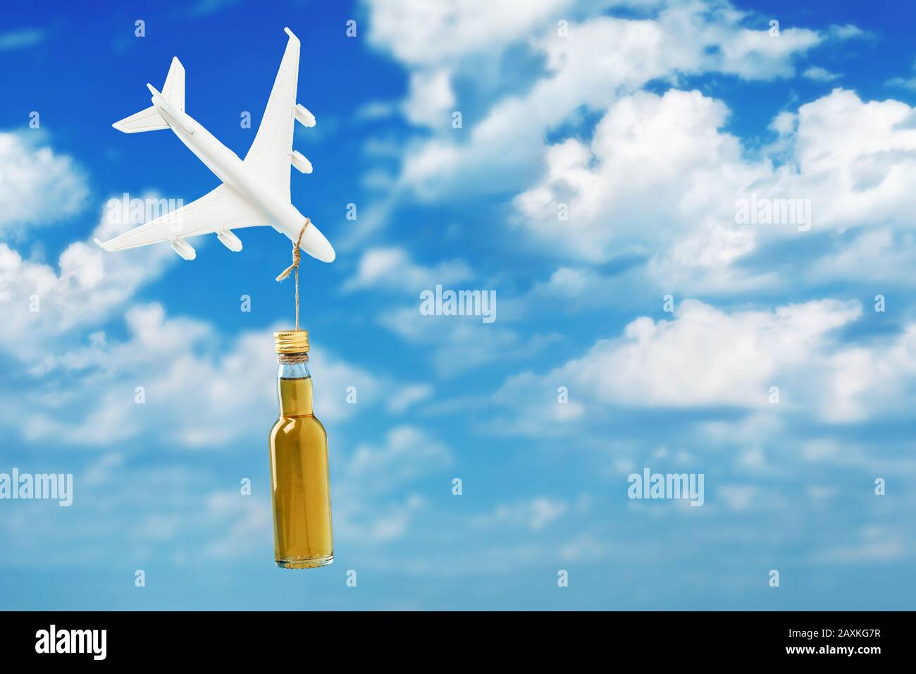 Toy plane and a bottle of whiskey on a background of sky with clouds