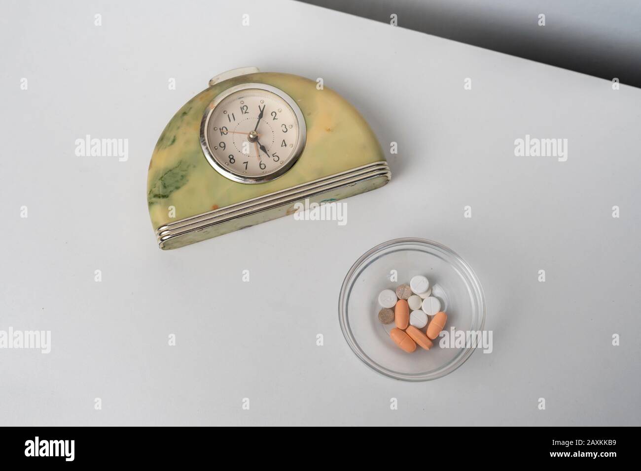the alarm clock on the shelf with the medicine pills, treatment
