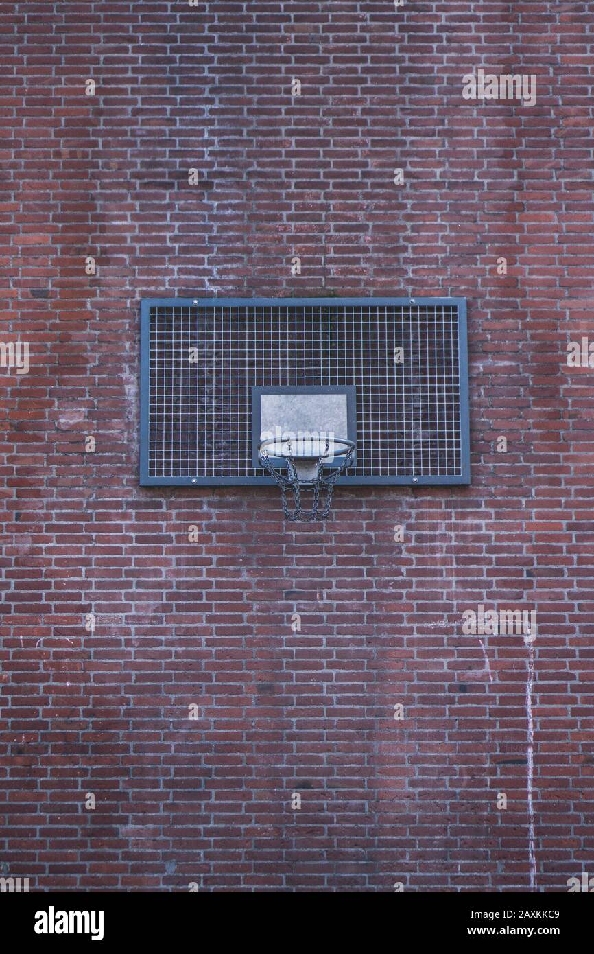 Wide shot of a basketball ring on a brick wall of a building Stock