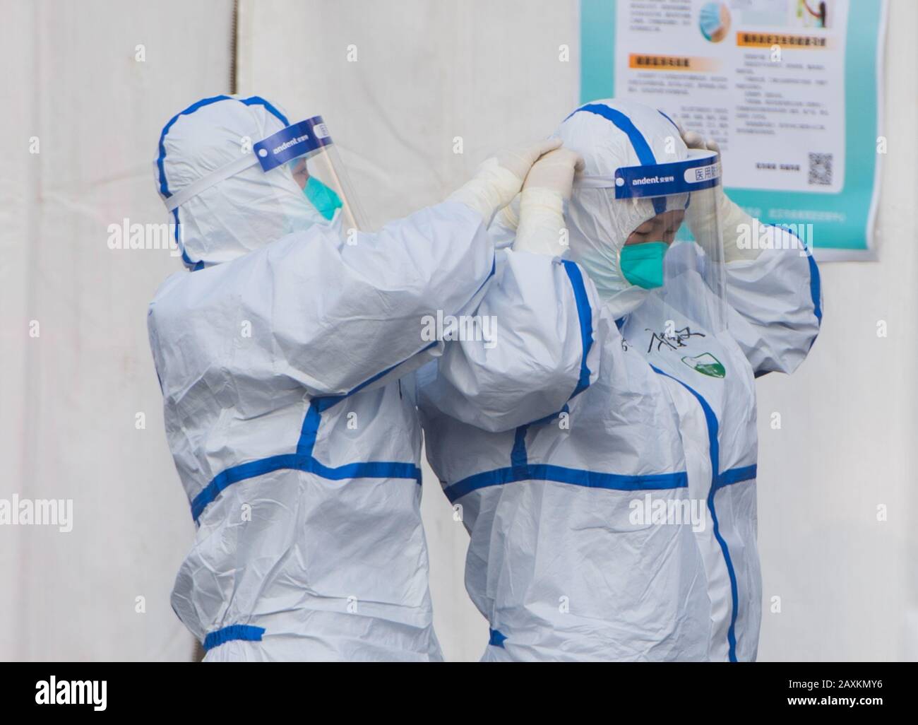 Wuhan, China's Hubei Province. 12th Feb, 2020. Jiang Yu (L) from east China's Anhui Province checks her colleague Chen Liying's protective suit at the temporary hospital converted from Wuhan Sports Center in Wuhan, central China's Hubei Province, Feb. 12, 2020. The temporary hospital converted from Wuhan Sports Center, with a total of 1,100 beds, started on Wednesday to admit patients with mild symptoms caused by the novel coronavirus. Credit: Xiao Yijiu/Xinhua/Alamy Live News Stock Photo