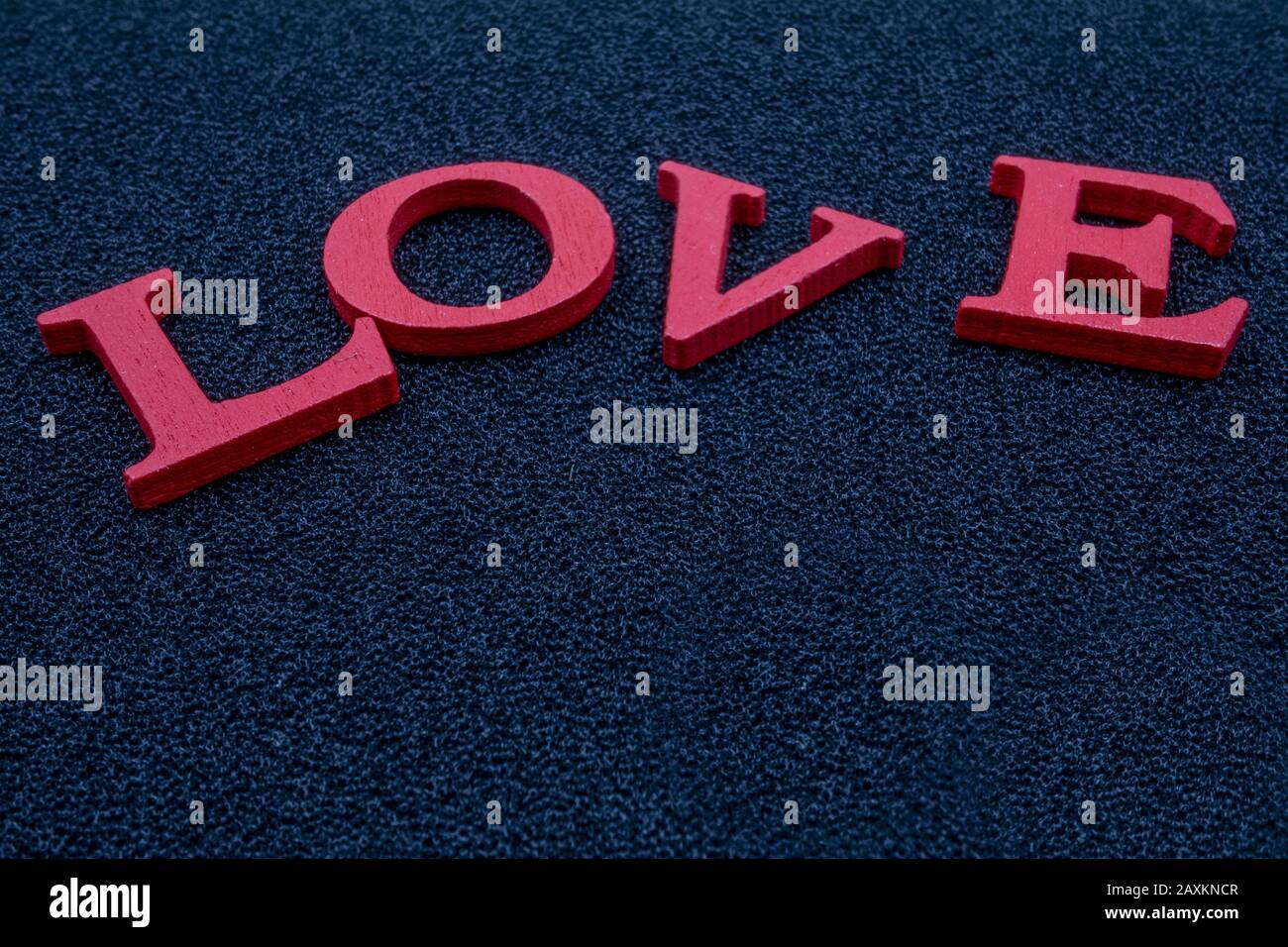 Closeup shot of red letter wood blocks that spells out 'love' on a blue rug Stock Photo