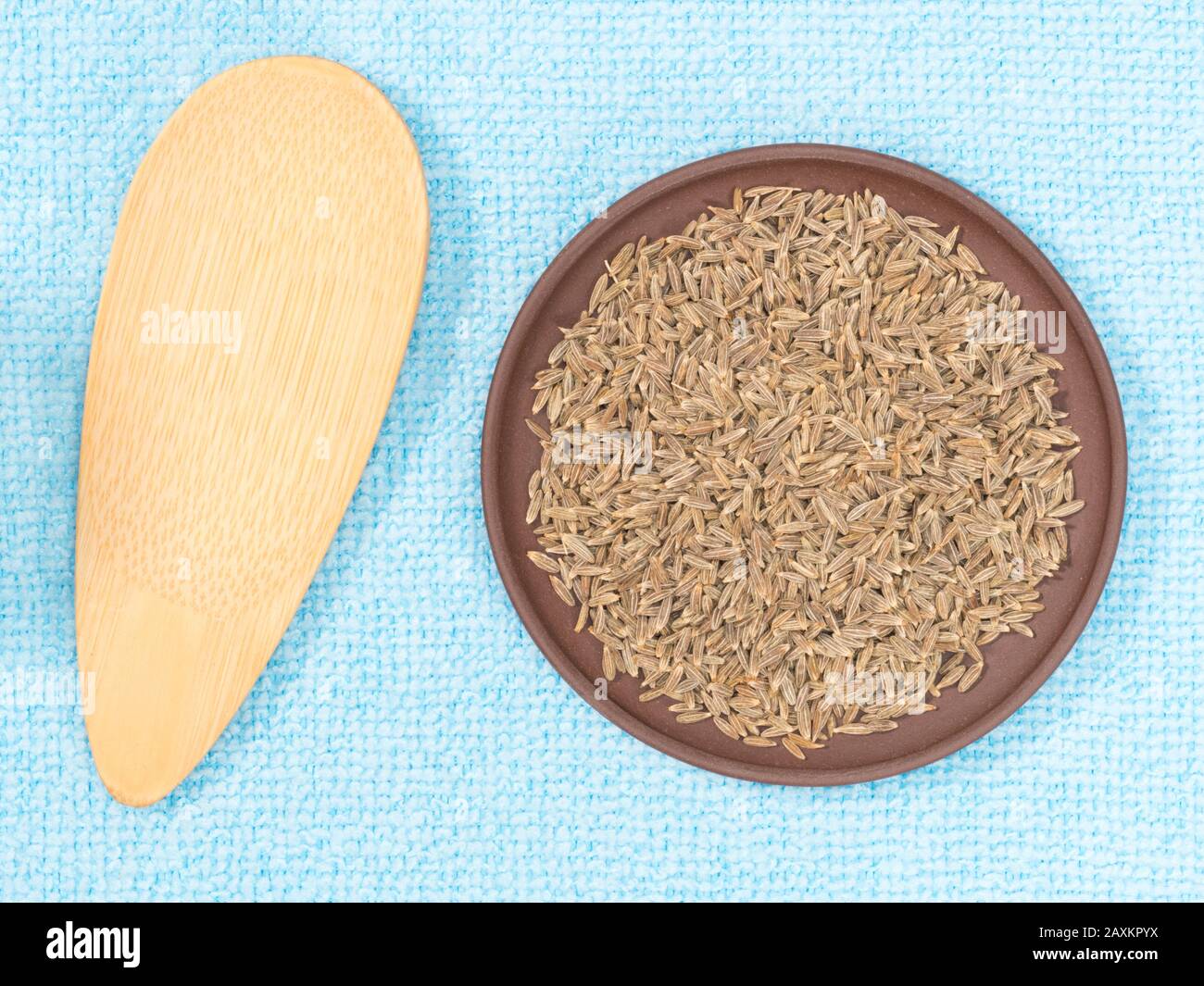 Cumin (jeera) in clay plate on blue fabric background Stock Photo