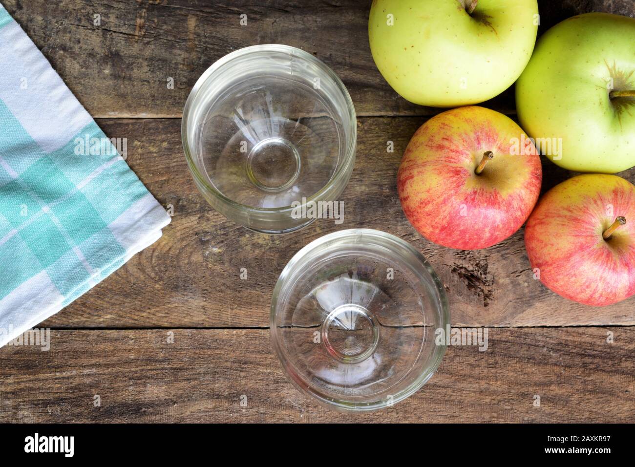 https://c8.alamy.com/comp/2AXKR97/old-wood-table-with-some-apples-two-empty-glasses-and-a-white-and-green-tablecloth-2AXKR97.jpg