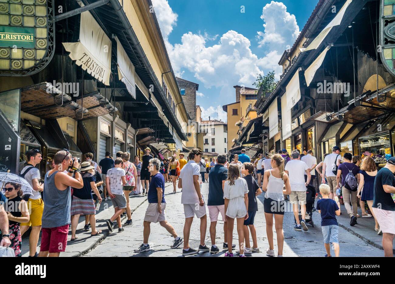 the Ponte Vecchio medieval stone arch bridge across the river Arno in Florence is lined  by the shops of jewelers, art dealers, and souvenir sellers, Stock Photo
