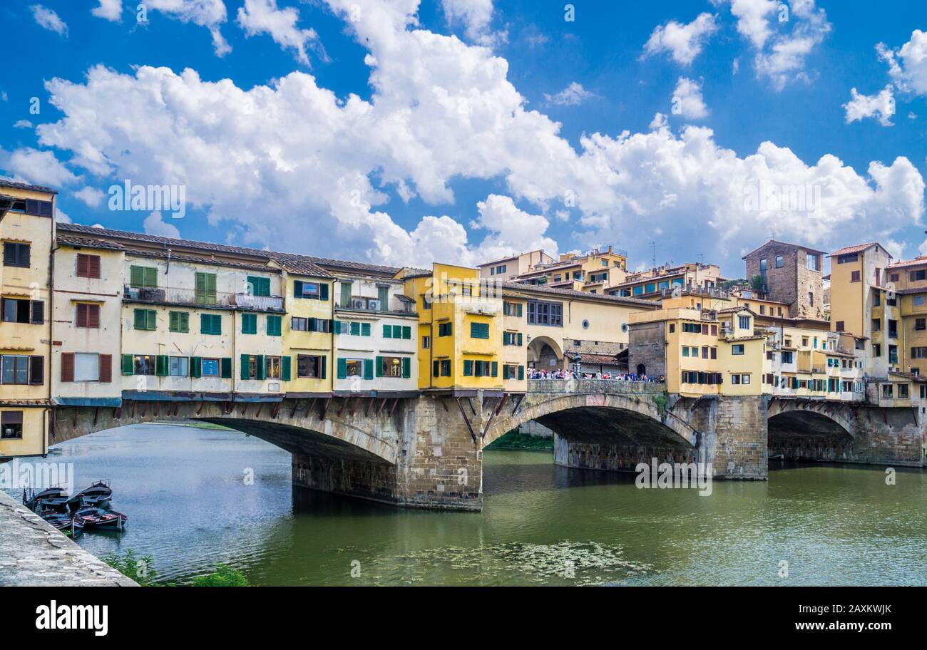 the Ponte Vecchio medieval stone arch bridge across the river Arno in Florence is lined  by the shops of jewelers, art dealers, and souvenir sellers, Stock Photo