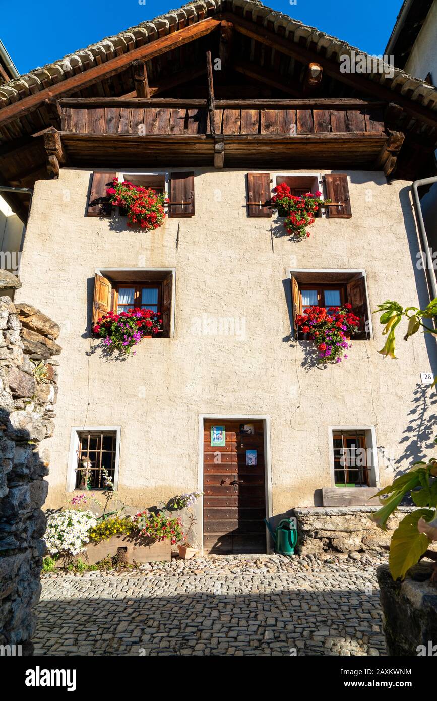House facade decorated with flowerpot in the old alley of Soglio, canton of Graubunden, Switzerland Stock Photo