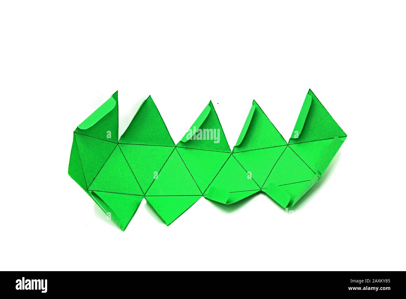 Geometric shape cut out of green paper and photographed on white background. Geometry net of platonic solids Icosahedron. 2-dimensional shape that can Stock Photo