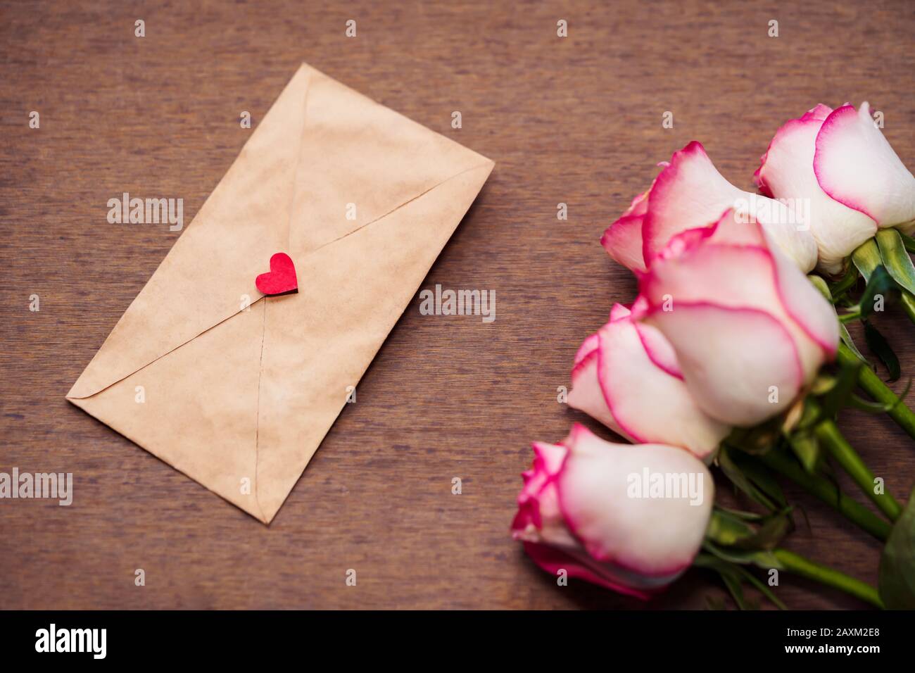 Pink rose bouquet with a love letter on vintage wooden surface. Background for anniversary, wedding, birthday card, invitation, cover, pamphlet. Stock Photo