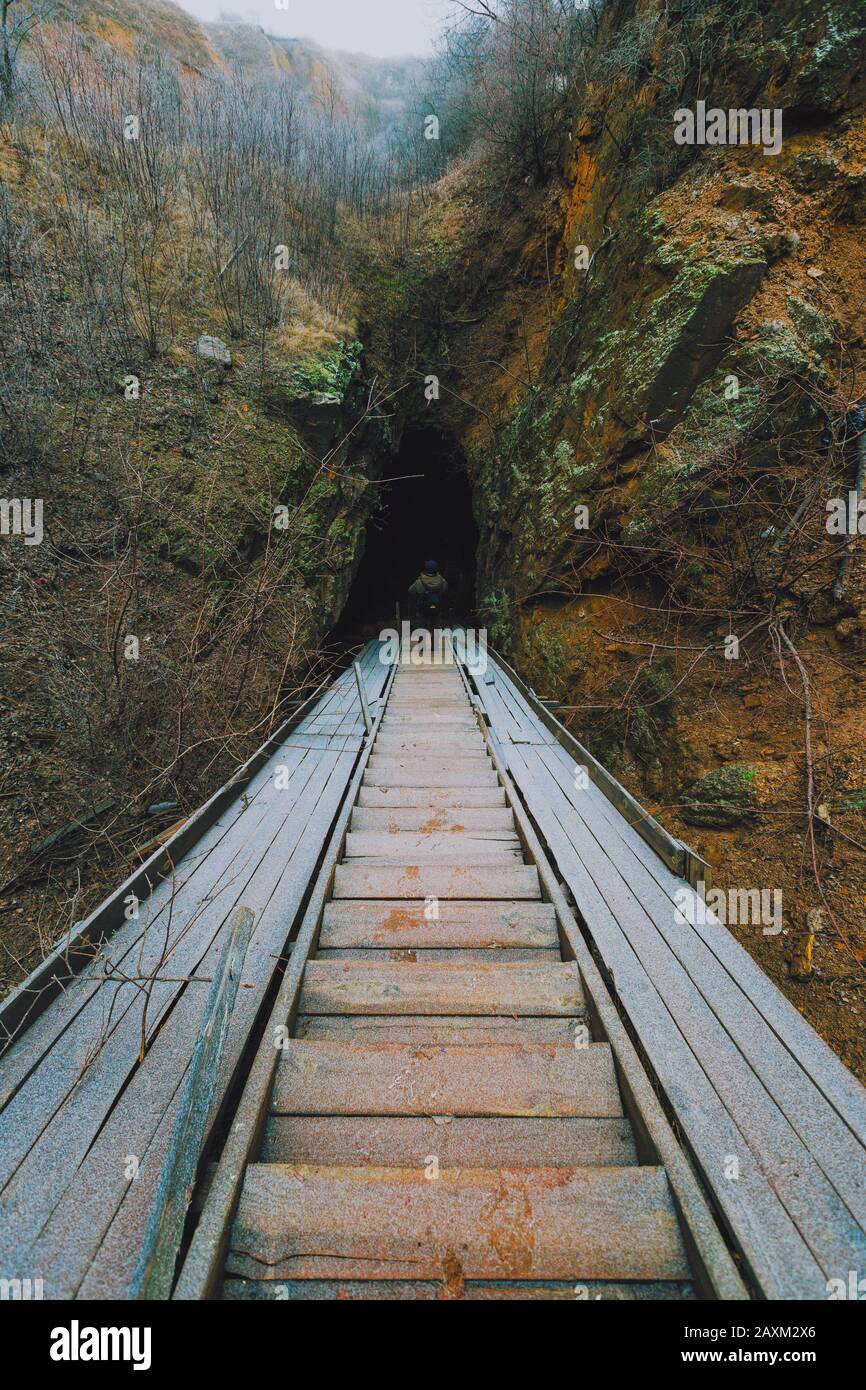 Stairway following to the excavated cave. Ancient mines in Ukraine. A traveler going down to the ancient adits Stock Photo